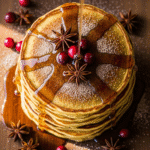 A close-up of golden easy pumpkin sausage pancakes stacked on a plate, drizzled with maple syrup.