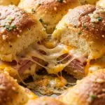 Close-up of easy baked ham cheese sliders with melted cheddar and Swiss on golden rolls